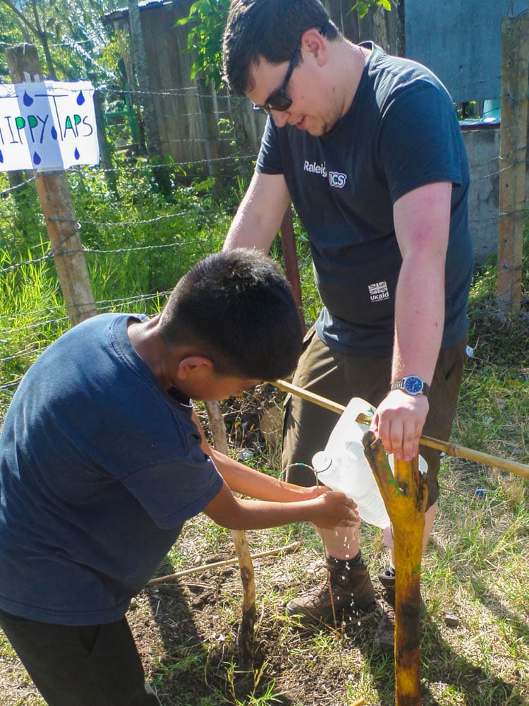 David helping one of the children in the community to wash his hands with a tippy tap.