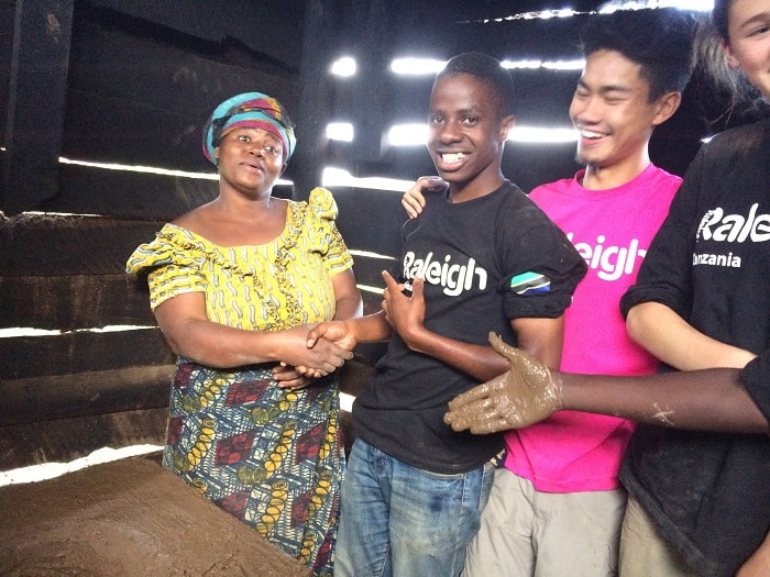 Kelvin, Elvis and Eleanor shaking hands with a villager after helping to build a rocket stove
