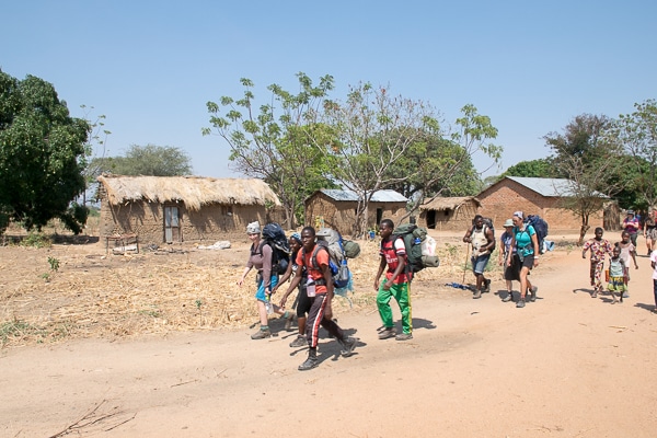 Trekking through village with children following