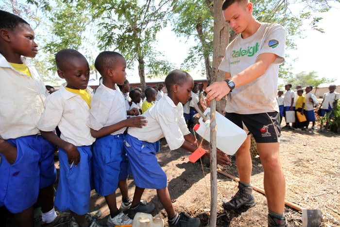Volunteer on water and sanitation project. Raising awareness of tippy tap and handwashing to school children