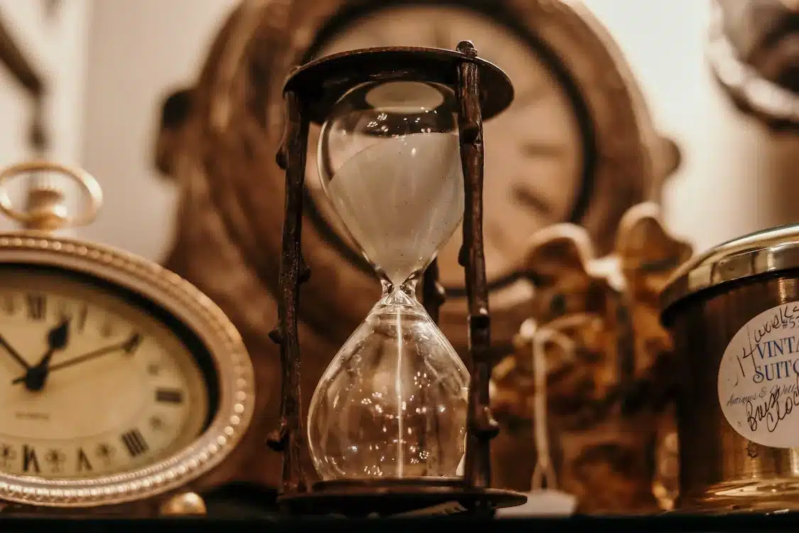 Close-up of an old hourglass with more clocks in the background