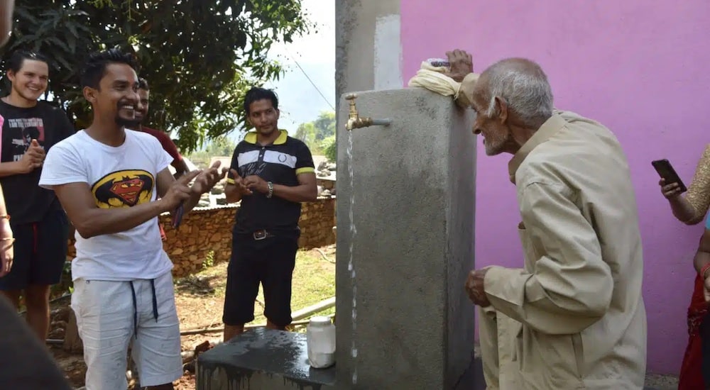 Leader of the Water User Committee opening the tap stand with the locals