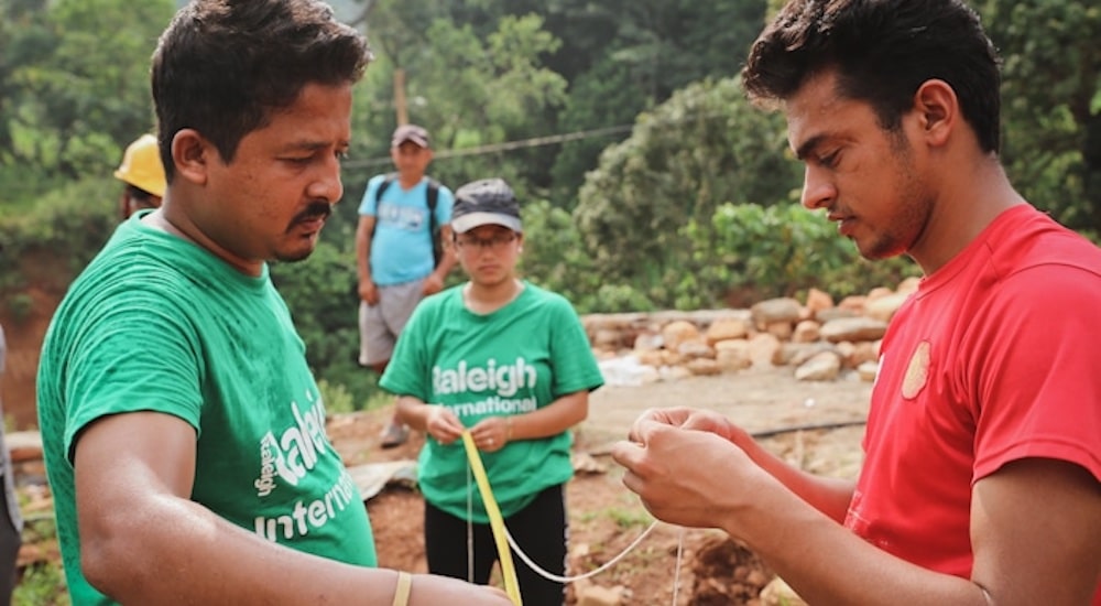 volunteers working together and holding a string and ribbon outdoors
