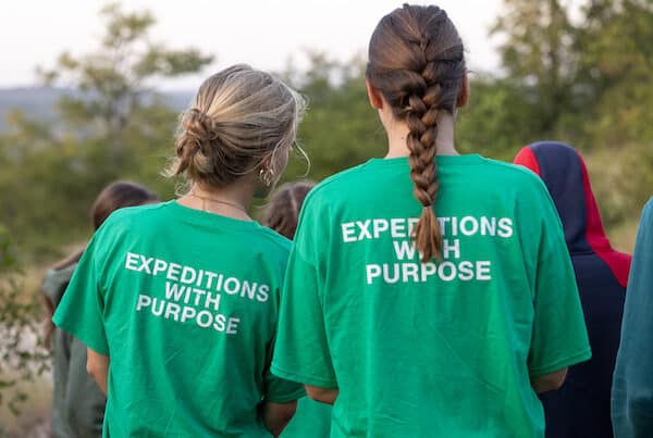 back view of 2 girls wearing green shirt that says "expeditions with purpose" at the back