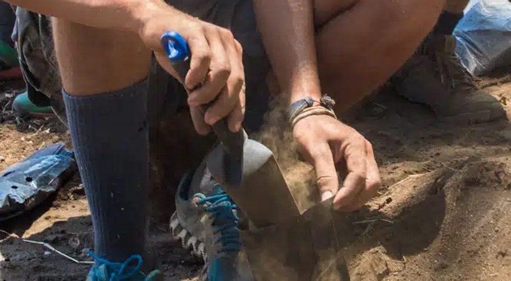 a volunteer using a hand trowel to dig soil