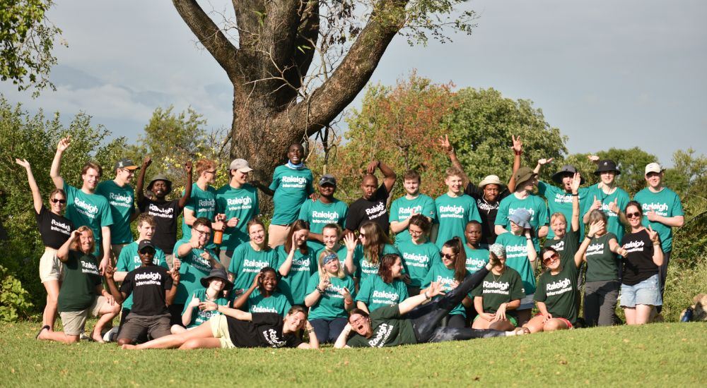 A group of Raleigh Volunteers gathered together, smiling and posing for a photo.