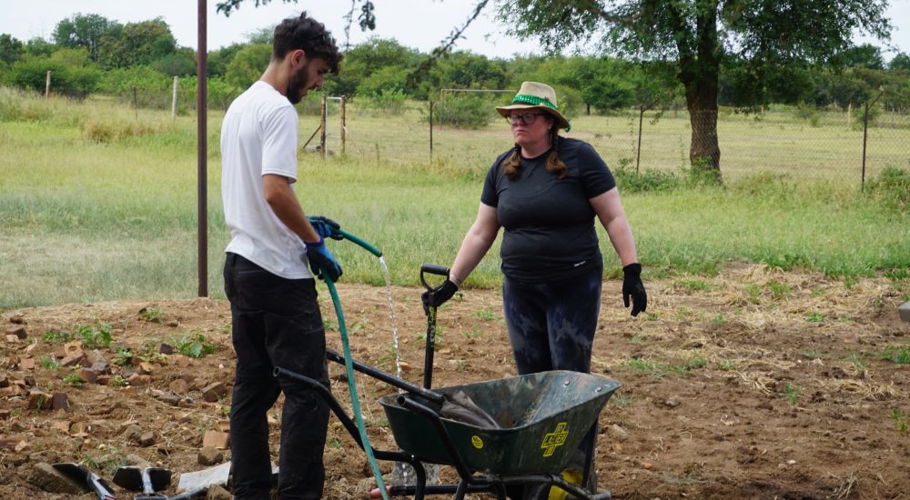 Two Raleigh Volunteers working together in a field.