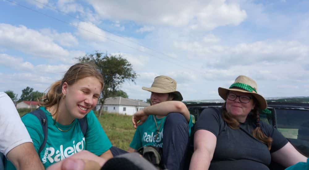 Three Raleigh Volunteers sitting in the back of a pickup car.